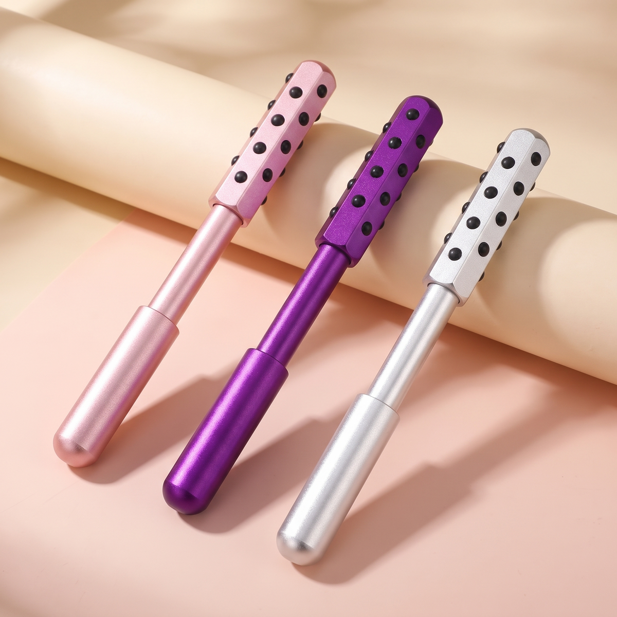 Germanium facial massage wand in rose, violet and silver on a cream and blush backdrop